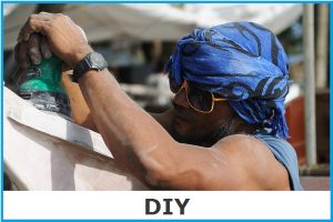 Online Mall DIY image link of a man using an electric orbital sander to shape a fibreglass boat.